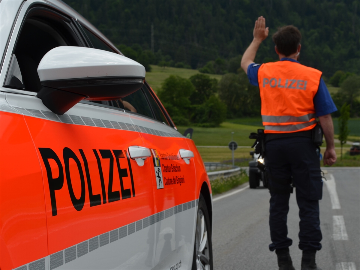 Fahrzeugseite eines Patrouillenfahrzeuges mit einem Polizisten im Hintergrund, der den Verkehr aufhält.