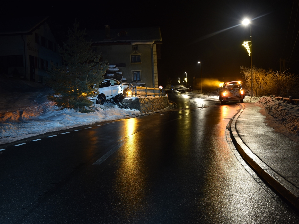 Der Strassenverlauf nach dem Bahnübergang in Surava. Rechts im Bild ein Patrouillenfahrzeug der Polizei. Links neben der Strasse erhöht, das Unfallfahrzeug. Eingeklemmt zwischen Stützmauer und einer Tanne.