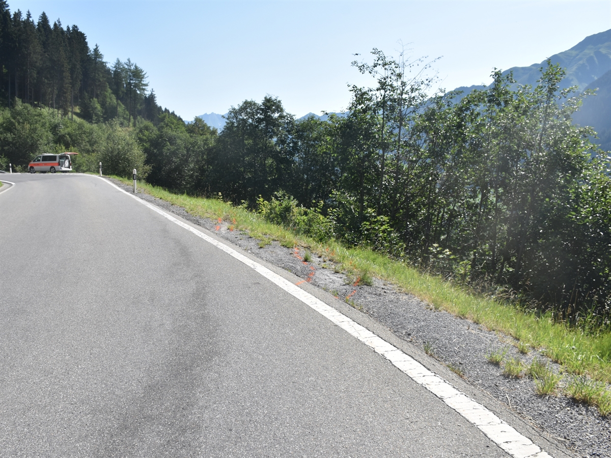 Die Lugnezerstrasse mit eingezeichneten Spuren über die Fahrbahnrand hinaus und die Böschung hinunter. Auf der Strasse steht ein Polizeiauto