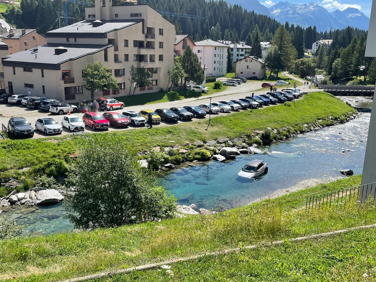 Das Auto steht mitten in der durch grüne Böschung führende, türkisfarbenen Moesa.