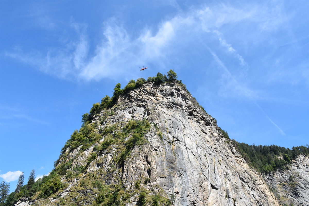 Felswand in Richtung Hohenrätien gesehen. Im blauen Himmel ist der Helikopter der Rega zu erkennen.