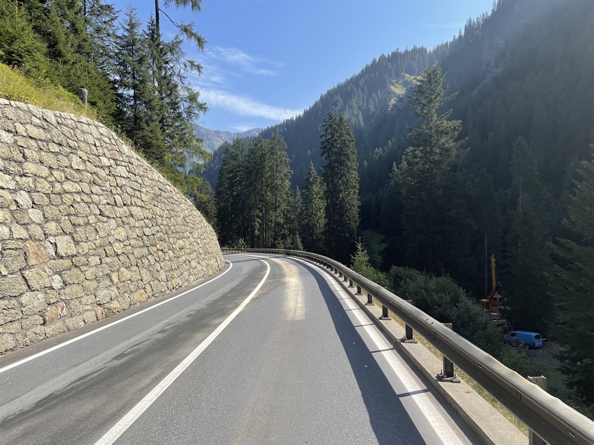 Eine Ölspur überzieht die ganze Fahrbahn. Blauer Himmel umgeben von Wald und Strassenkörper.