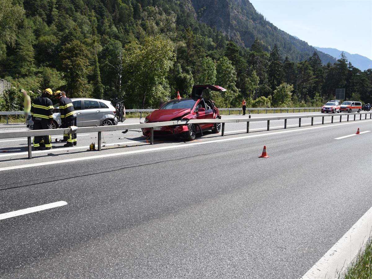 Feuerwehrleute stehen bei den Unfallfahrzeugen auf der Nordspur der A13. Im Hintergrund Polizeifahrzeuge, welche die Nordspur blockieren.