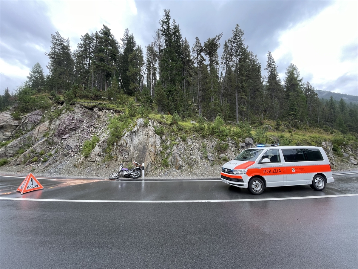 Links ein Faltsignal POLIZEI, rechts davon das beschädigte Motorrad und ein Polizeiauto. Dahinter ein bewaldeter Hügel.