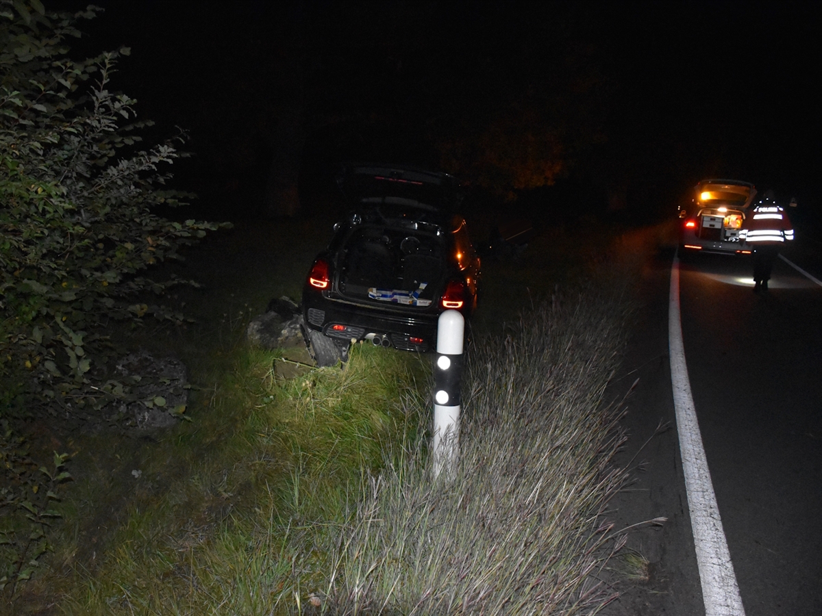 Links ausserhalb der Strasse auf Steinen das Unfallauto. Rechts davon die Strasse und ein Polizist. 