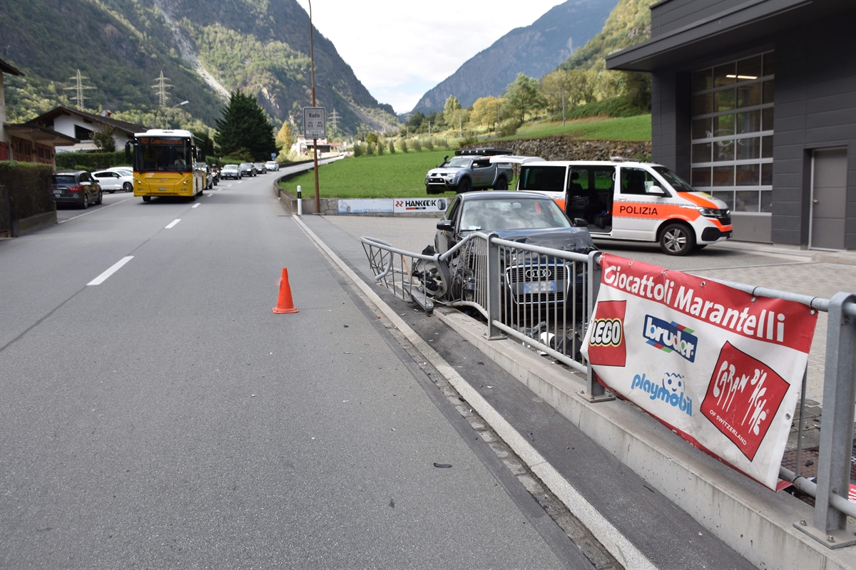 Strassenverlauf bei der Unfallstelle in Campocologno. Vorne rechts ist der totalbeschädigte Personenwagen hinter dem Geländer zu erkennen. Im Hintergrund steht ein Patrouillenfahrzeug der Polizei.