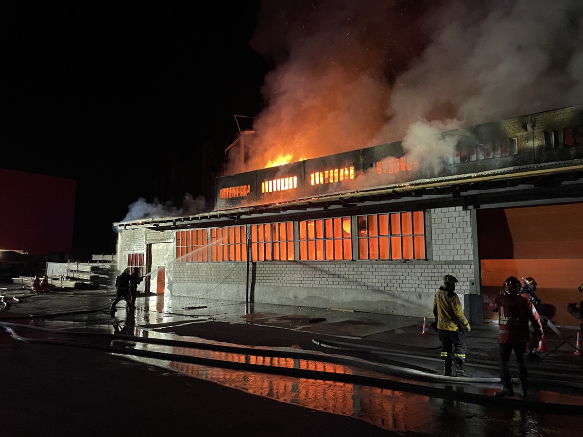 Lagerhalle in der Nacht in Vollbrand, Feuerwehrleute mit Schläuchen