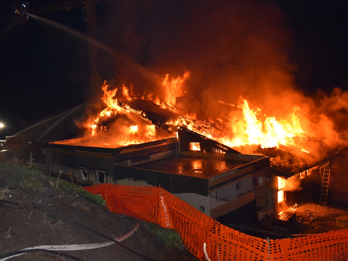 Das Bergrestaurant Foppa steht in Vollbrand. Feuerwehrleute spritzen aus drei Richtungen Wasser in die Flammen.