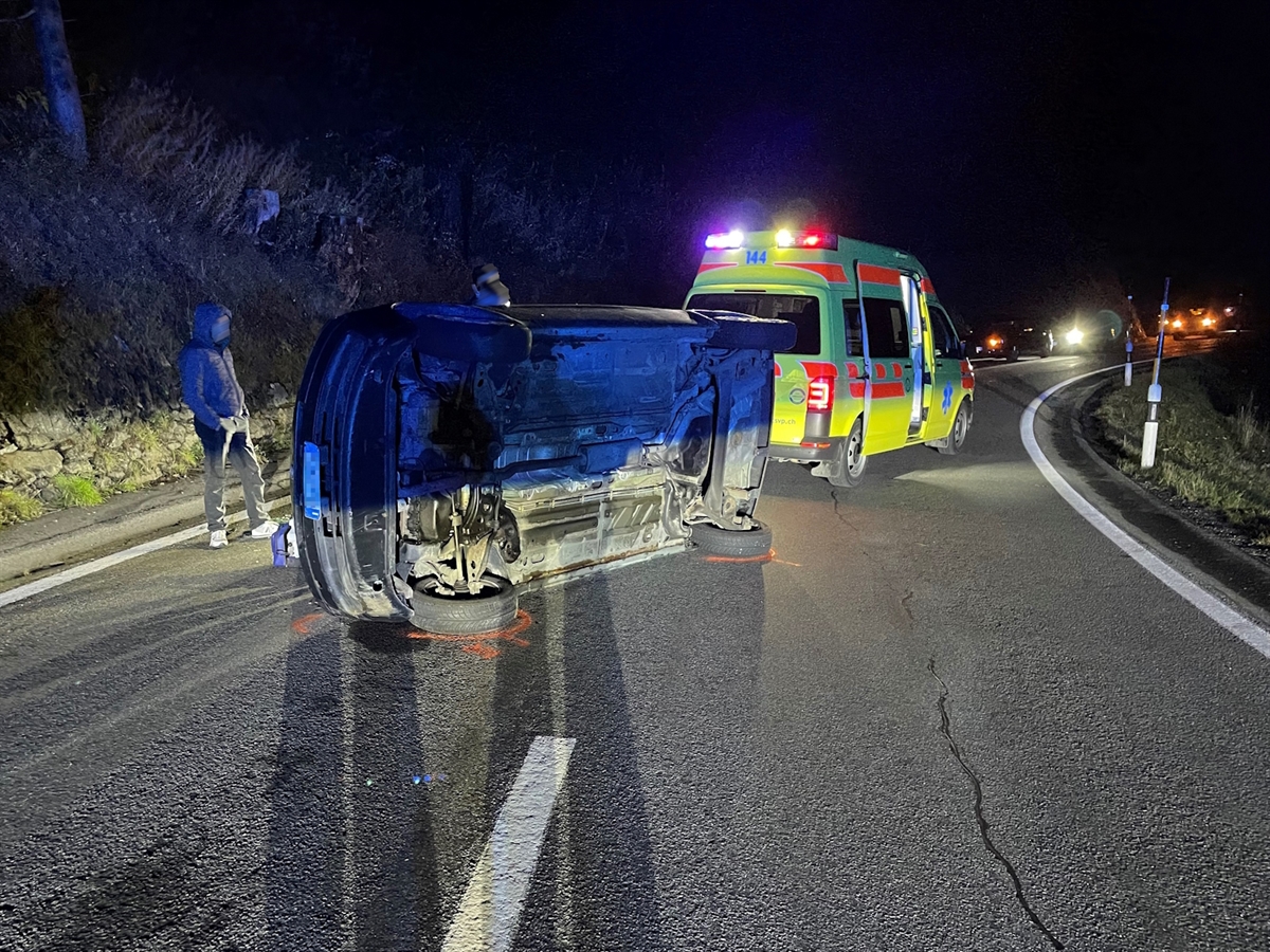 Im Vordergrund das auf der Seite liegende Auto. Dahinter ein Rettungswagen.