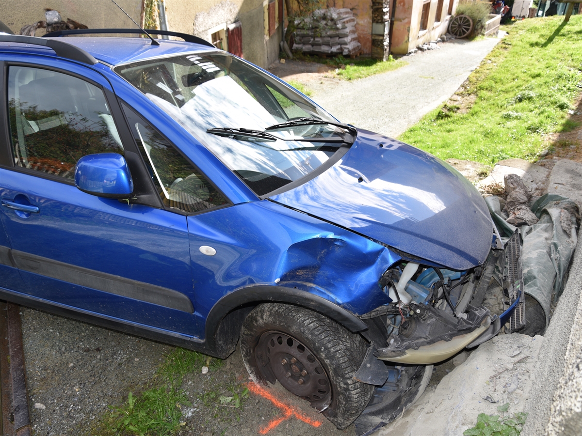 Das blaue Auto mit total beschädigter Front unmittelbar vor der Stallmauer.