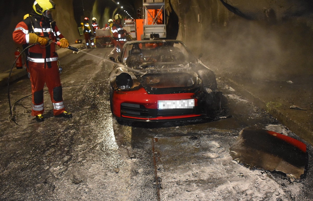 Abgebranntes Auto und Feuerwehrleute im Tunnel