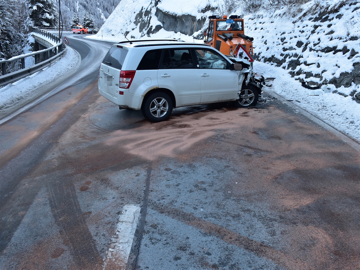 Das Unfallauto steht quer zur Fahrbahn hinter der Schneefräse. Im Hintergrund ein Polizeiauto. Die Strasse ist mit Ölbinder verschmiert.