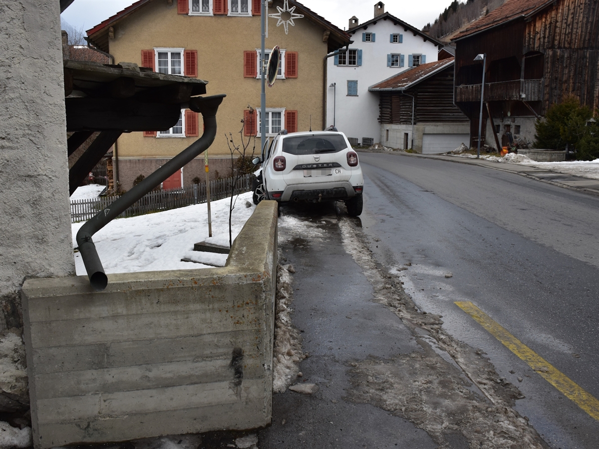 Links die Betonmauer, rechts die Strasse. Ein wenig im Hintergrund das Auto von hinten. Radaufhängung und Türe vorne links sind deformiert.