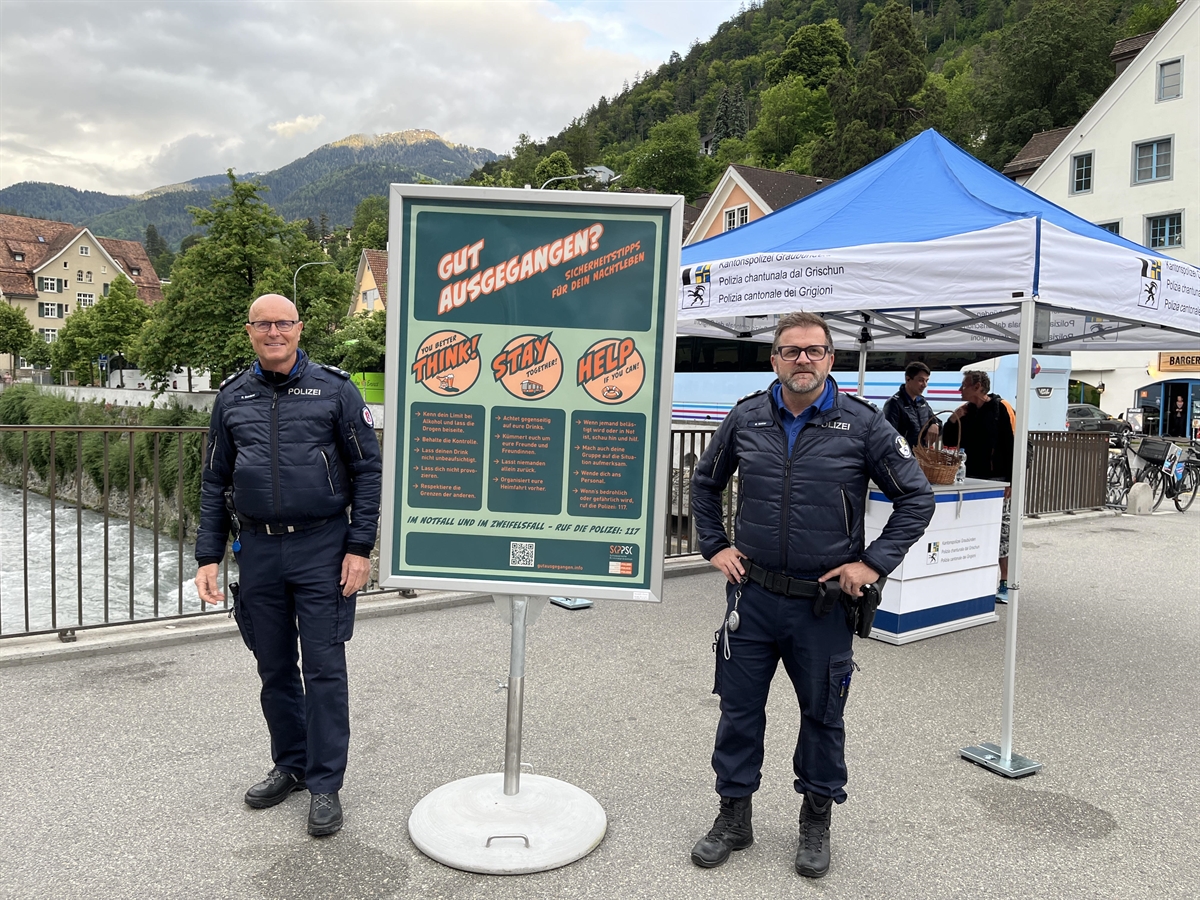 Stadtpolizist und Kantonspolizist vor Plakat am Stand an der Plessur